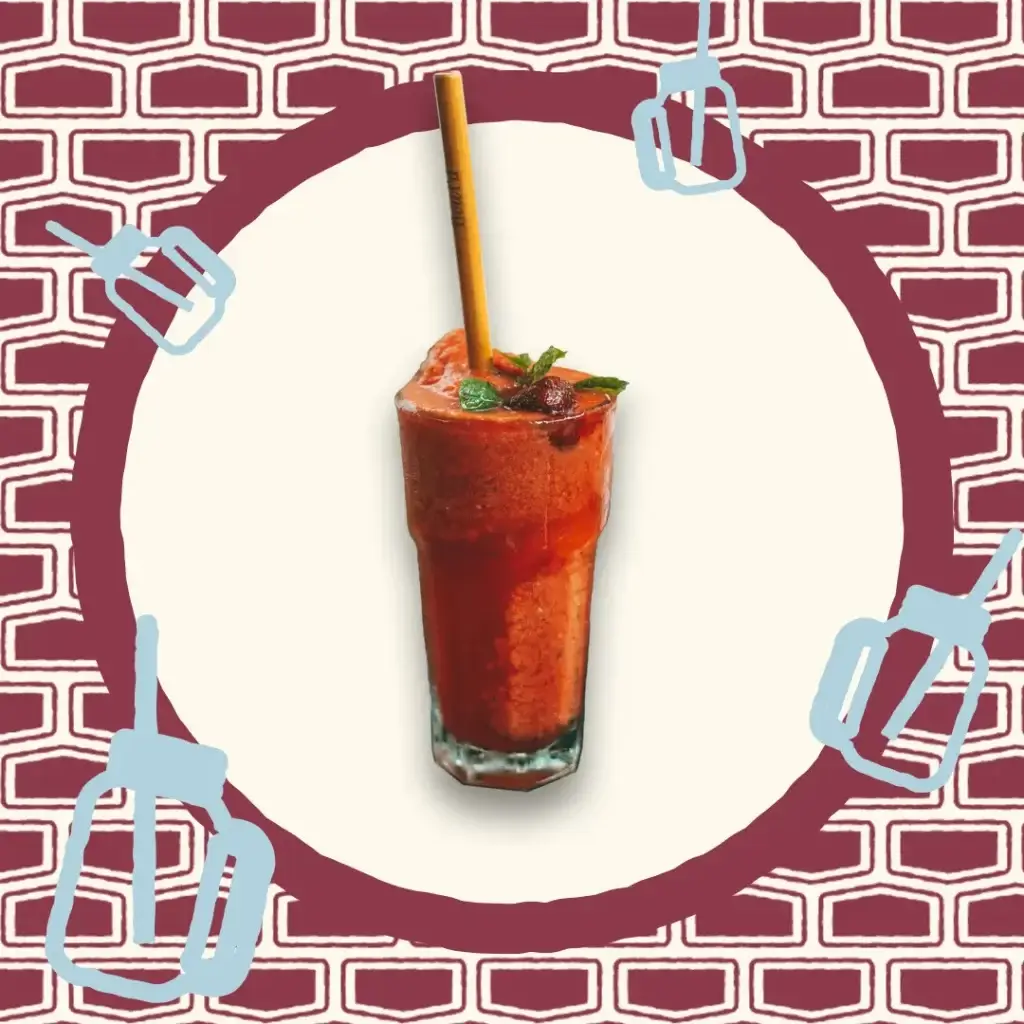 Smoothie rouge aux fruits, décoré de fruits rouges et servi avec une paille en bambou